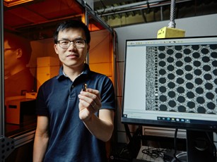 Dr. Li holding a chip in front of some techology